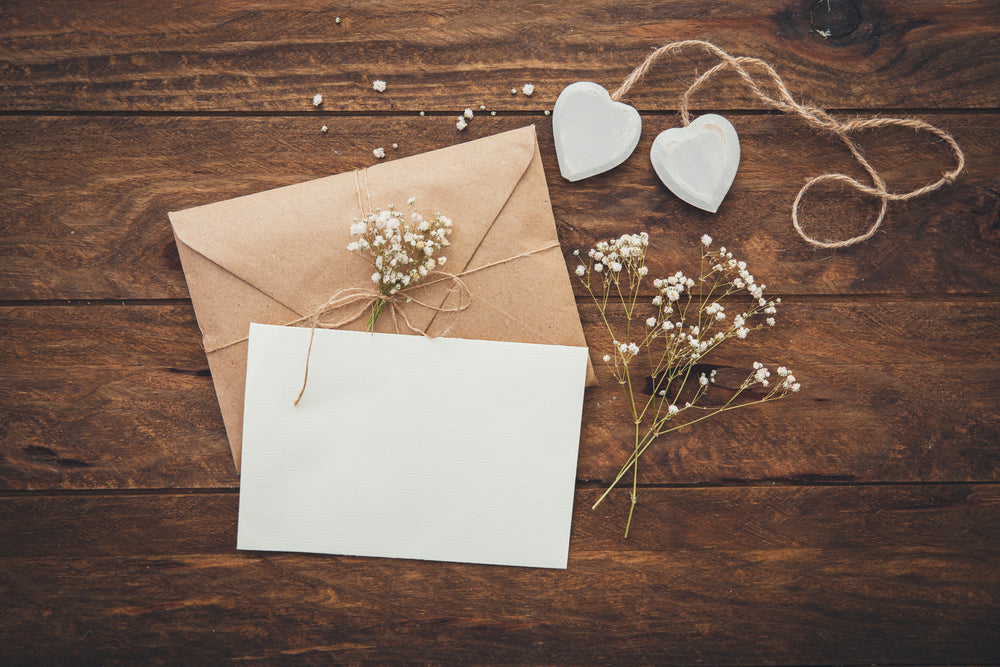 Empty greeting card and flowers with hearts on wooden background